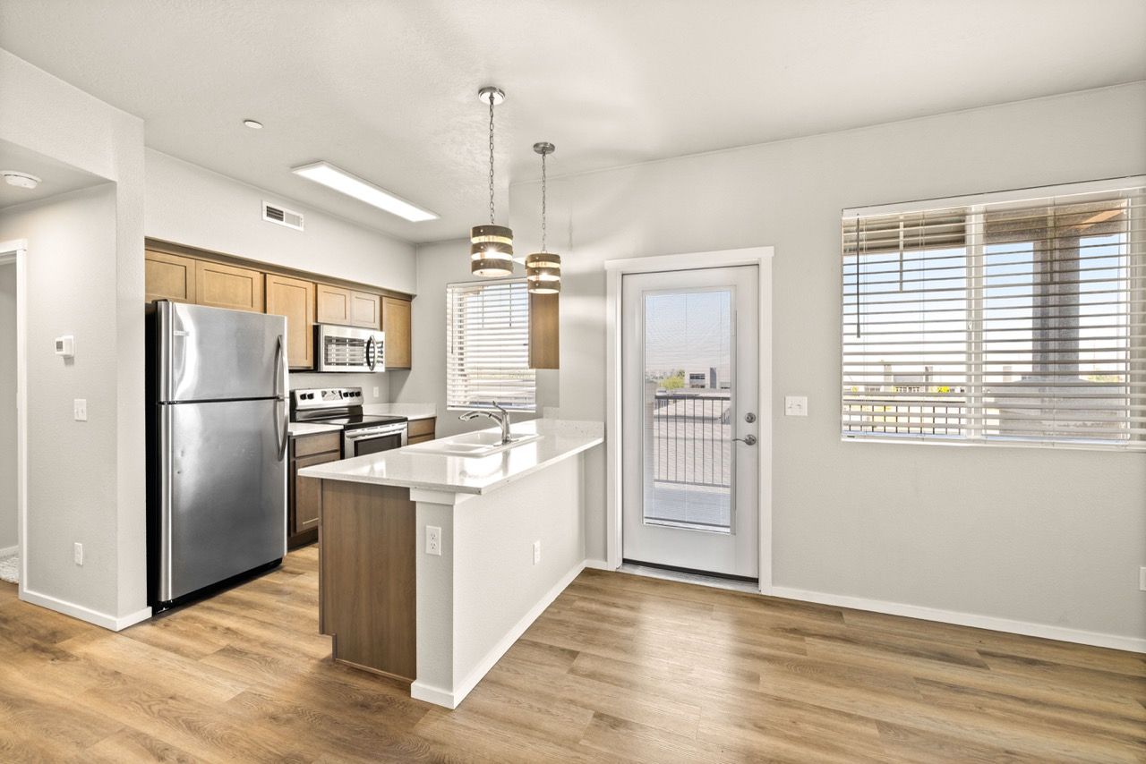 Open-concept kitchen with island, stainless steel appliances, and light wood cabinets at Olympus at Ten Mile, offering apartments in Meridian, ID.