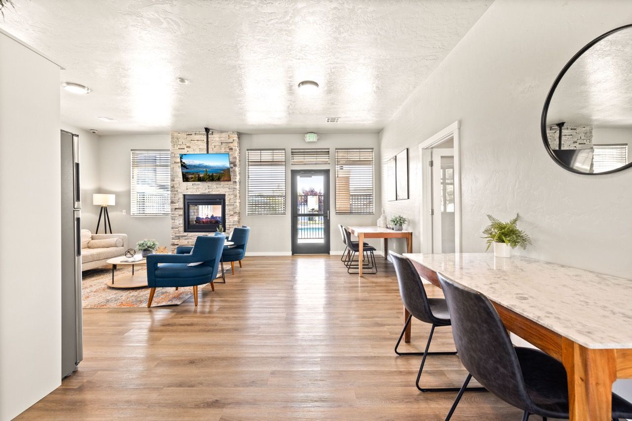 Bright community lounge with fireplace, TV mounted on a stone wall, blue armchairs, and a marble-topped island at Olympus at Ten Mile, offering pet-friendly apartments for rent in Meridian, ID.