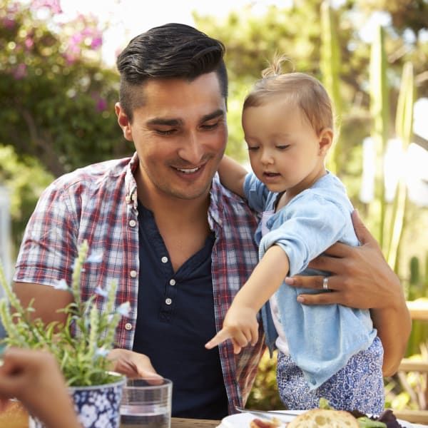 Man holding a child points at food on an outdoor table.