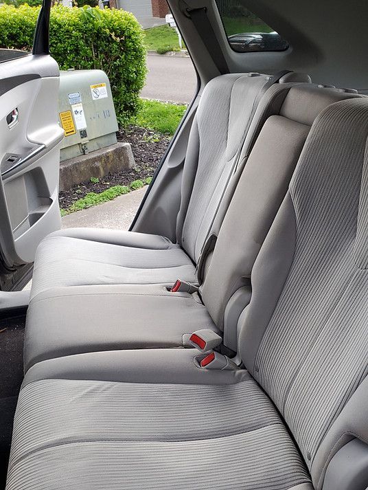 The back seat of a car with seat belts on it.