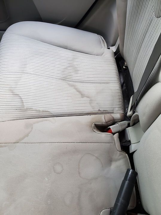 The back seat of a car with stains on it.
