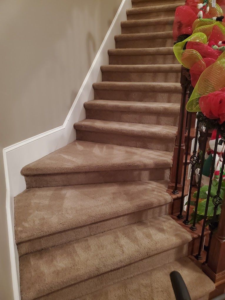 A staircase with carpeted steps and a railing decorated for christmas.