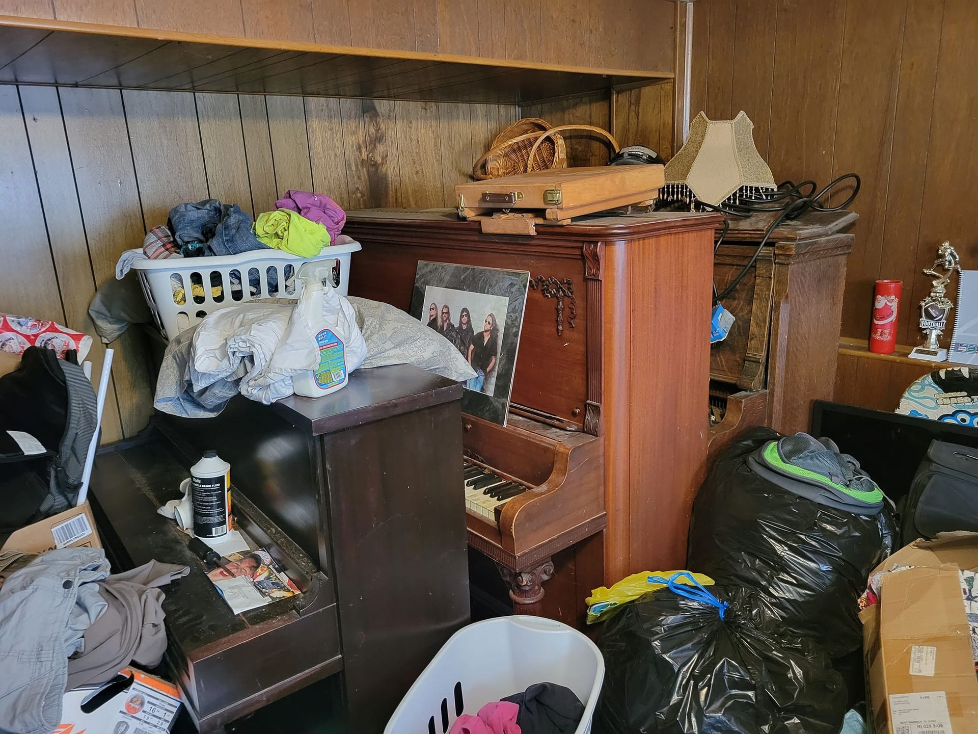 Upright piano and household furniture packed into a cluttered room before furniture removal in Board
