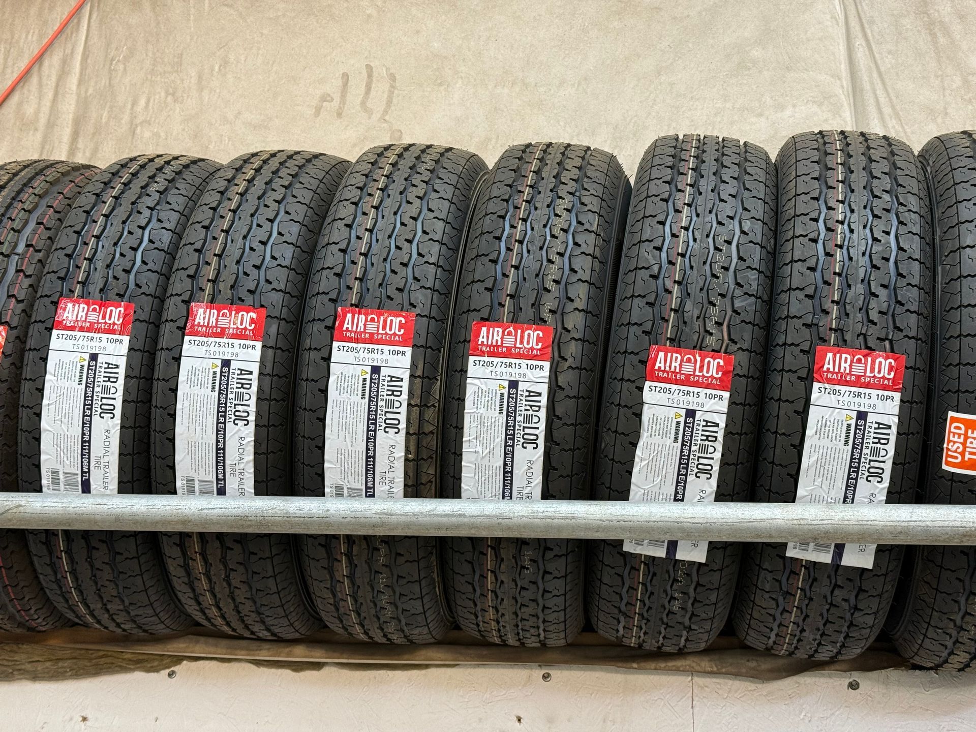 A row of new, black tires with red and white product labels hanging on a metal rack.