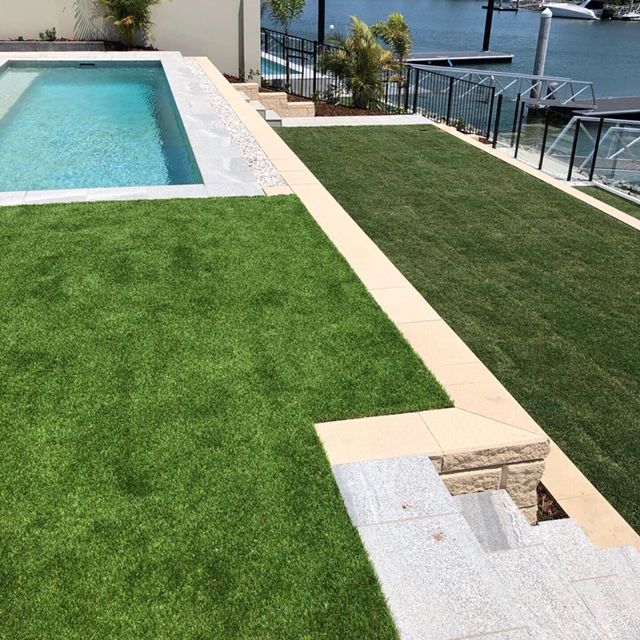 A large swimming pool is surrounded by a lush green lawn