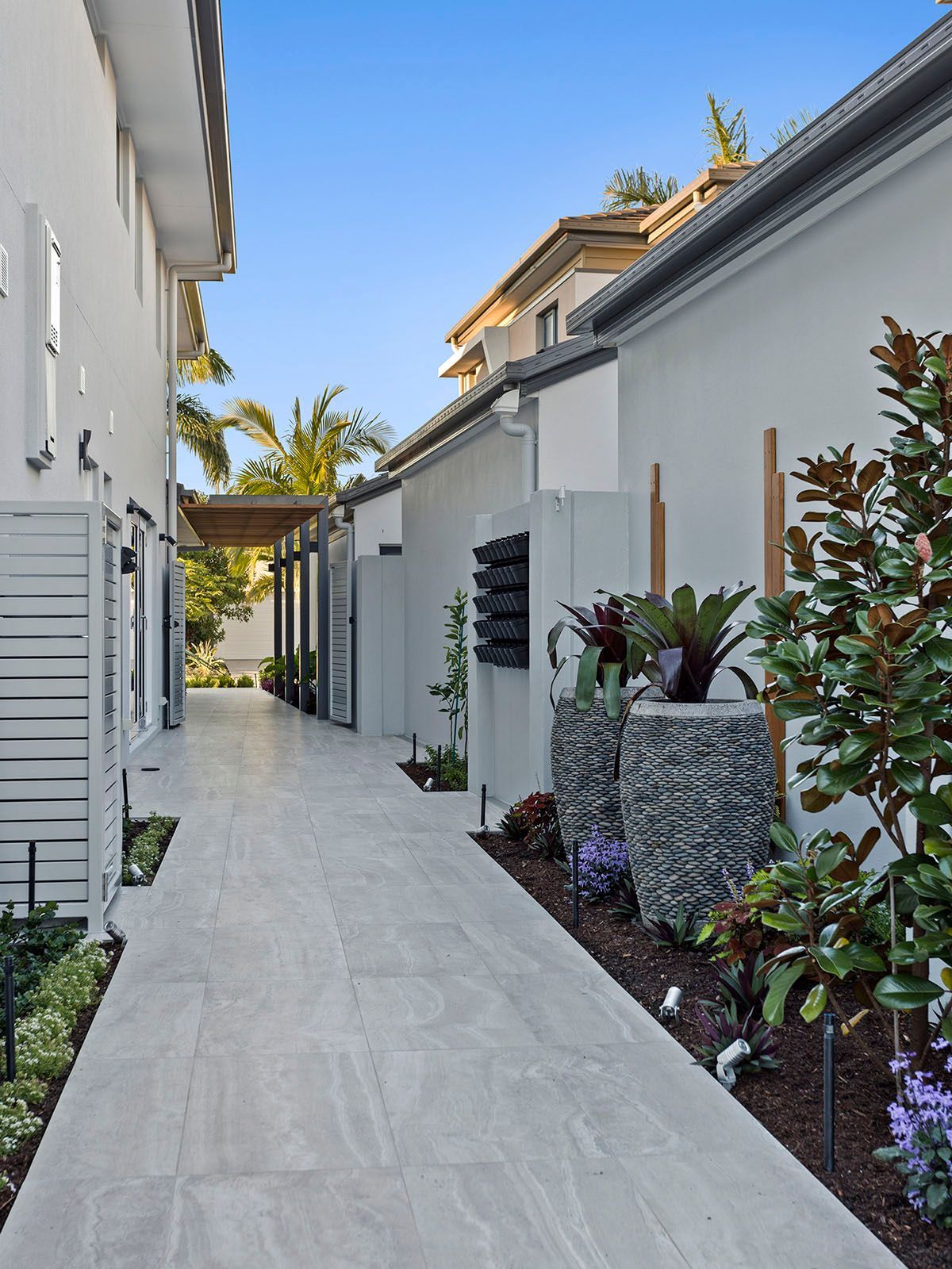 A walkway between two buildings with plants on the side