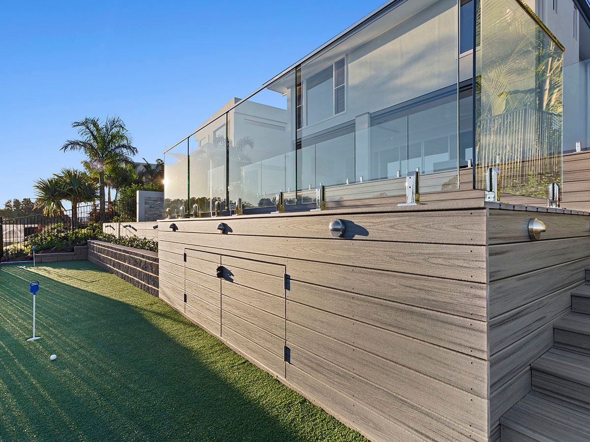 A wooden deck with a glass railing and stairs leading up to it.