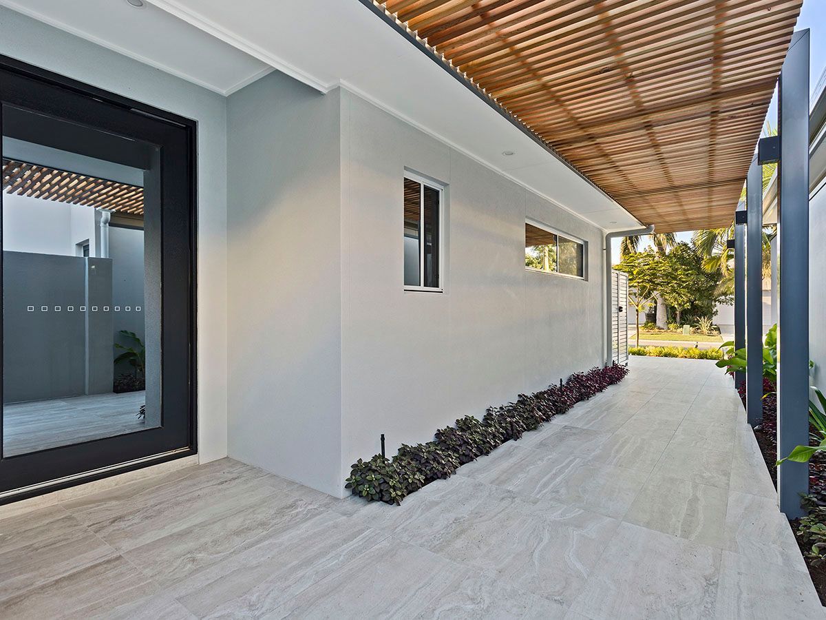 A long walkway leading to a house with a wooden roof.