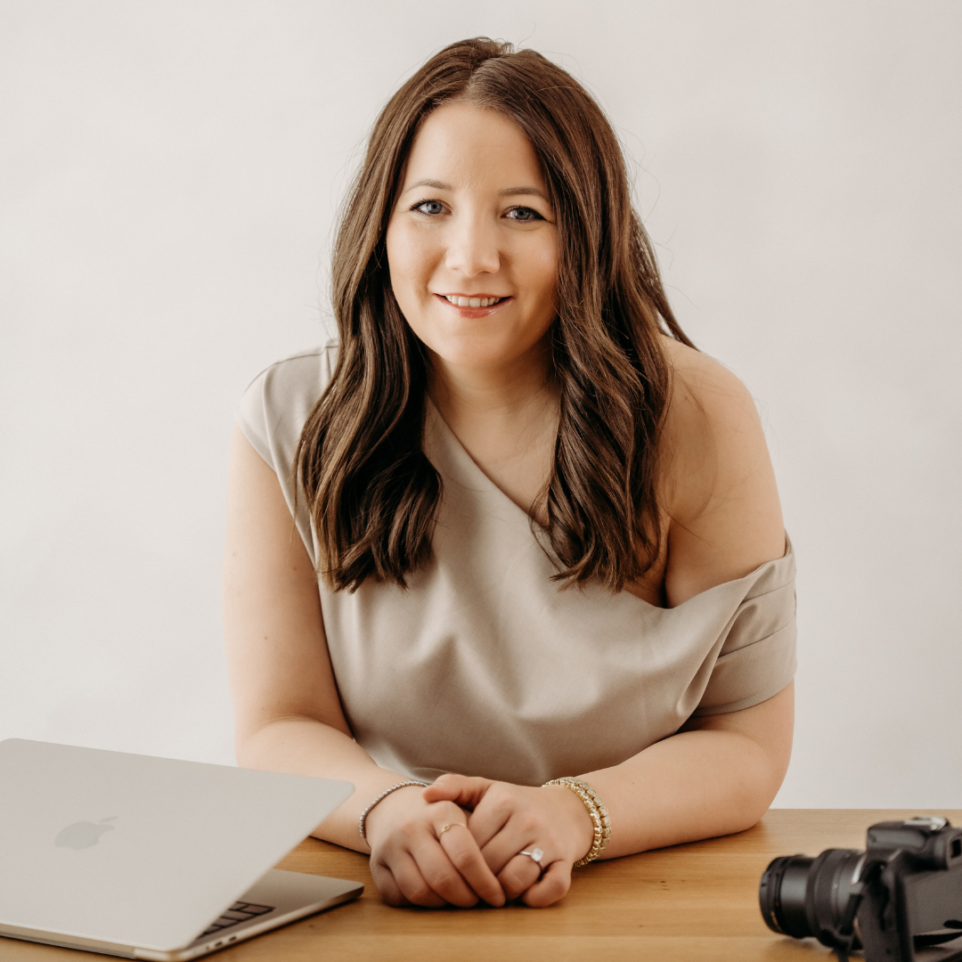Woman smiling at a desk with a laptop and camera