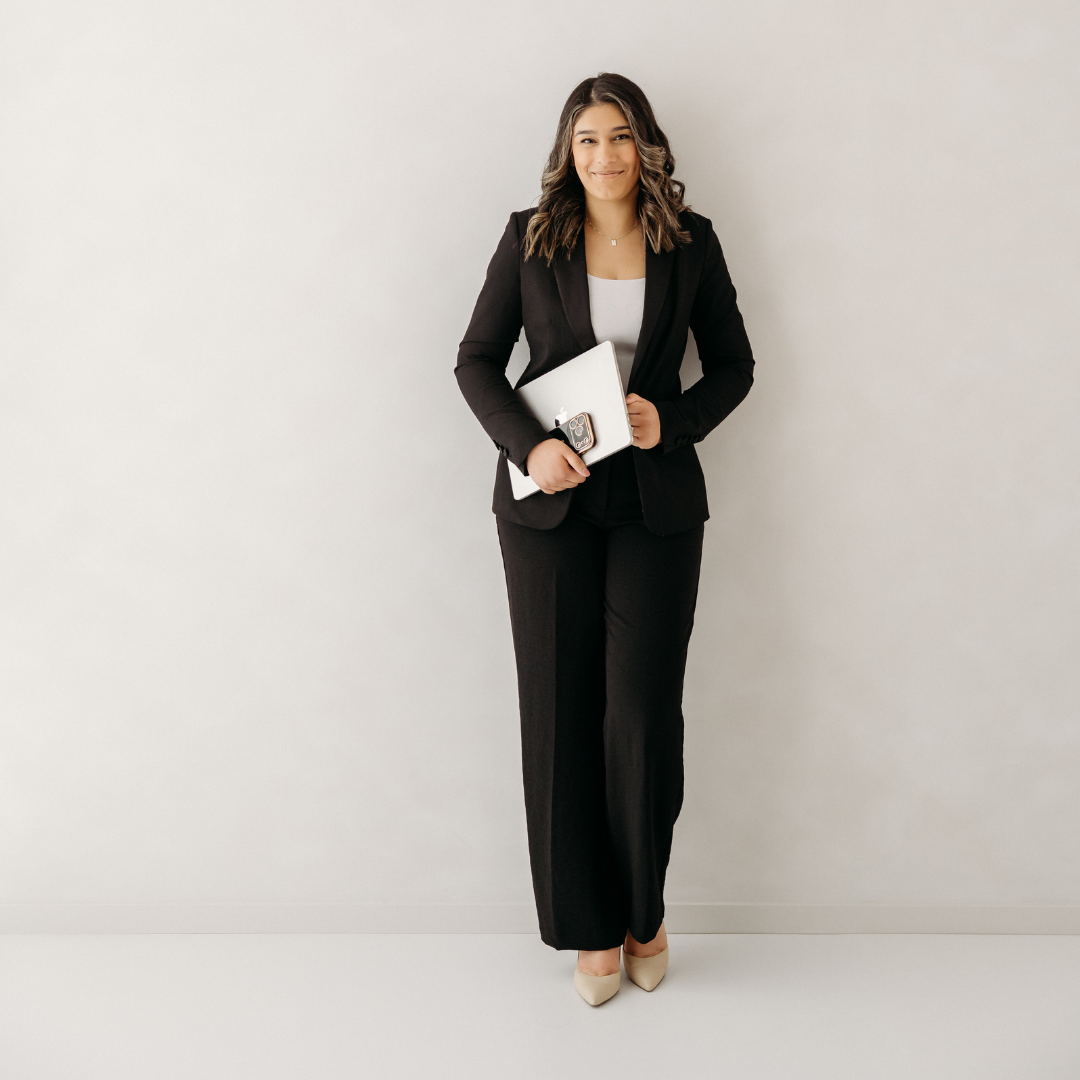 Woman in black suit standing against a white wall
