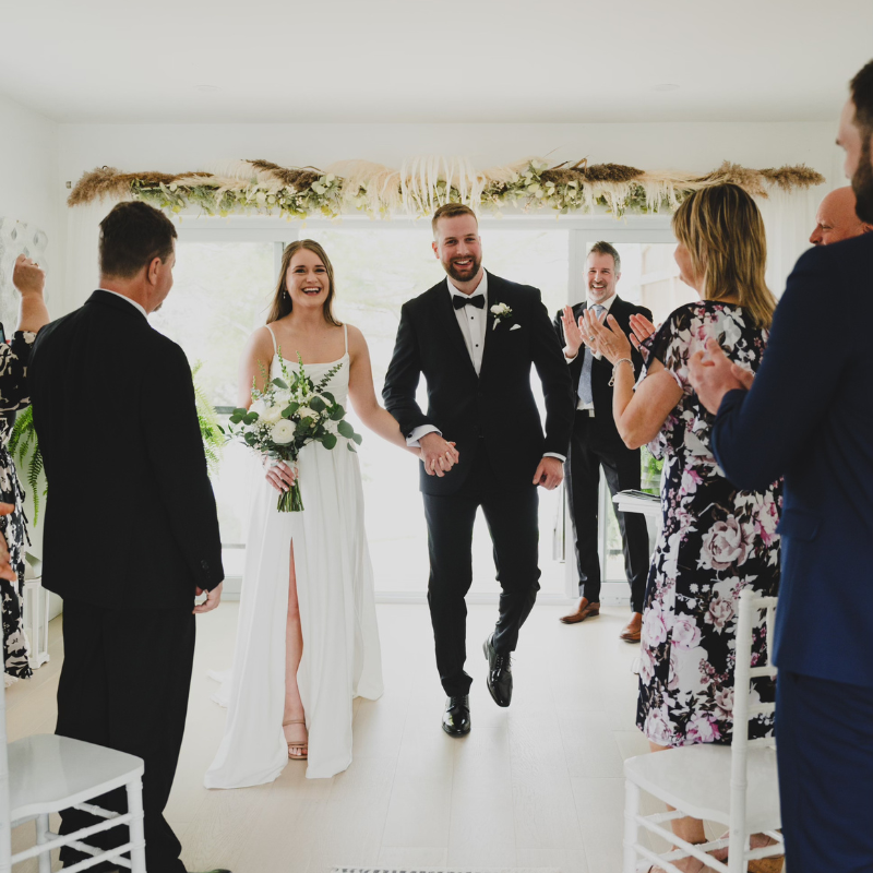 A bride and groom are walking down the aisle at their wedding