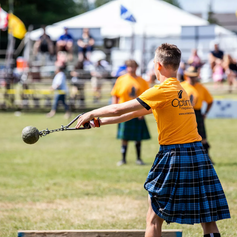 A man in a kilt is throwing a ball