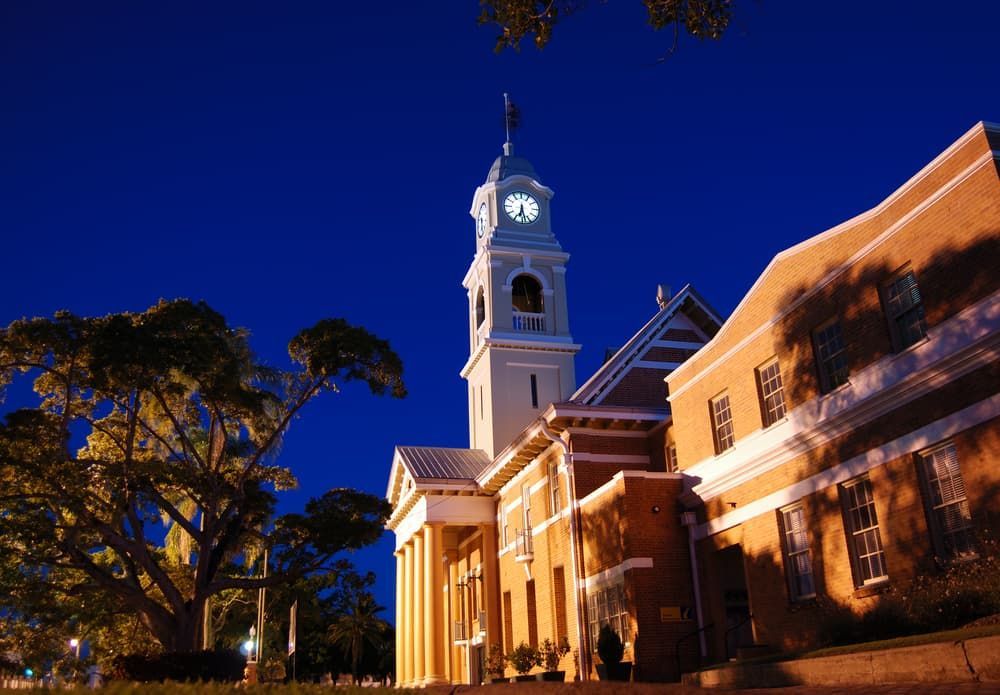 A Large Building With a Clock Tower at Night — Brett Negus Plumbing In Maryborough, QLD