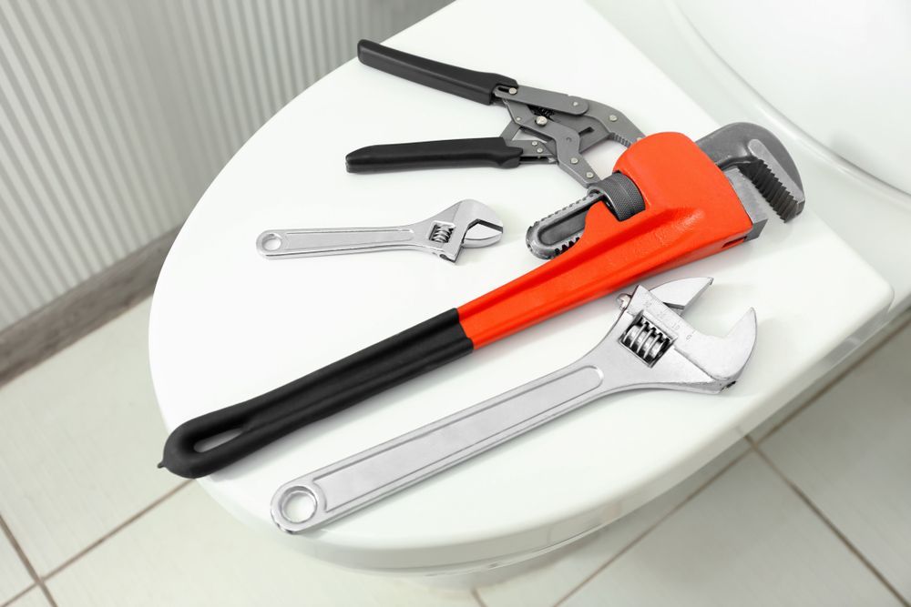 Plumber's Tools On Toilet Seat Lid — Brett Negus Plumbing In Oakhurst, QLD
