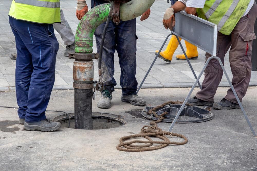 A Group of Construction Workers Are Working on a Manhole Cover — Brett Negus Plumbing In Oakhurst, QLD