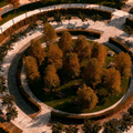Aerial view of a circular landscaped park with concentric paths and autumn-colored trees