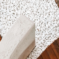 White pebble-covered ground with a beige stone block and a strip of wooden floor.