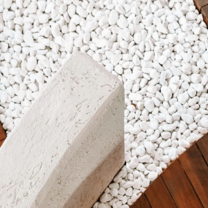 White pebble-covered ground with a beige stone block and a strip of wooden floor.