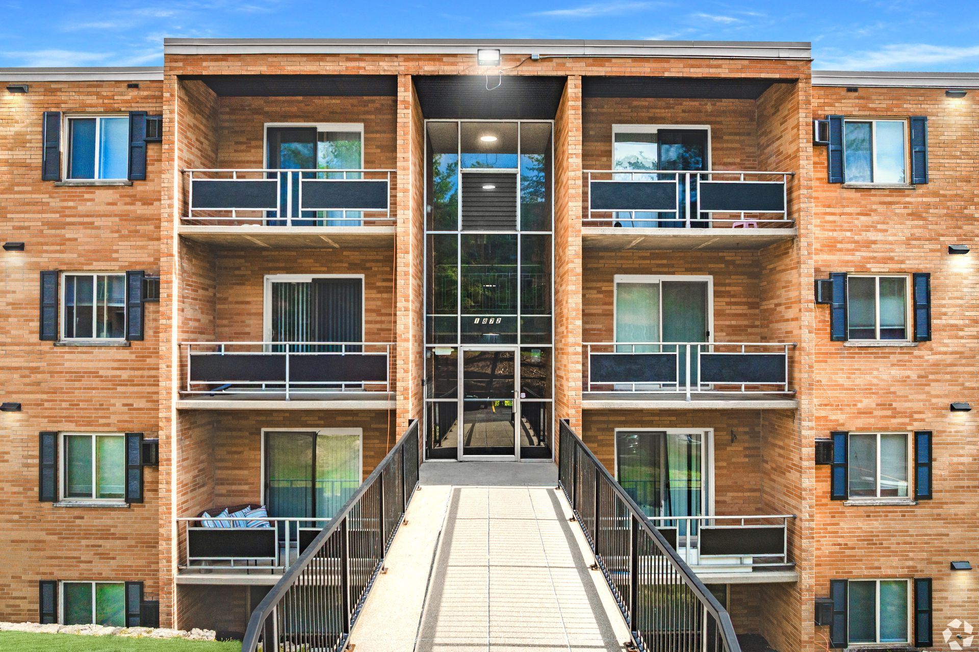 Brick apartment building at Overlook at Sunset with balconies, shutters, and a front walkway.