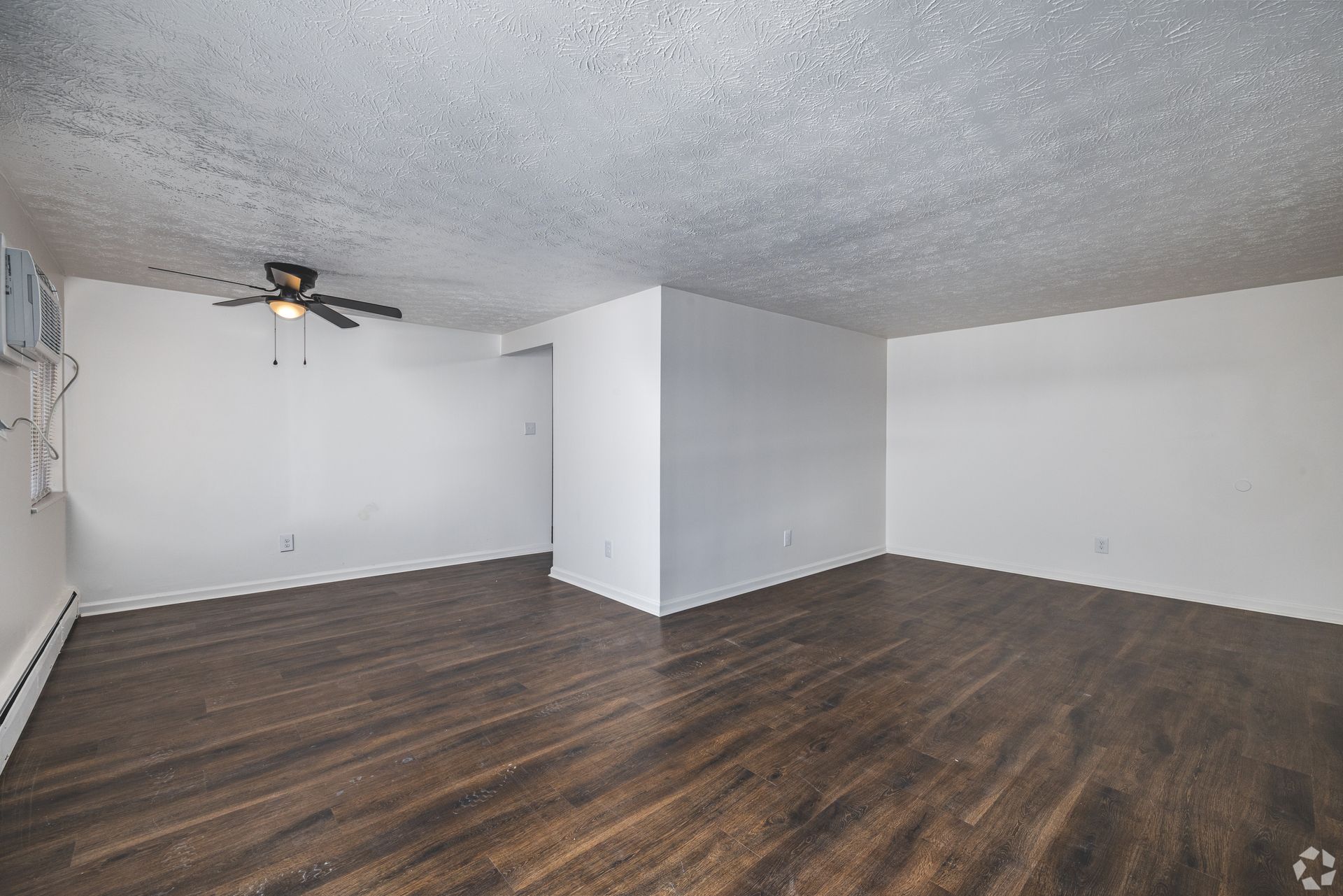 Spacious living room at Overlook at Sunset with wood-style flooring, ceiling fan, and neutral walls.