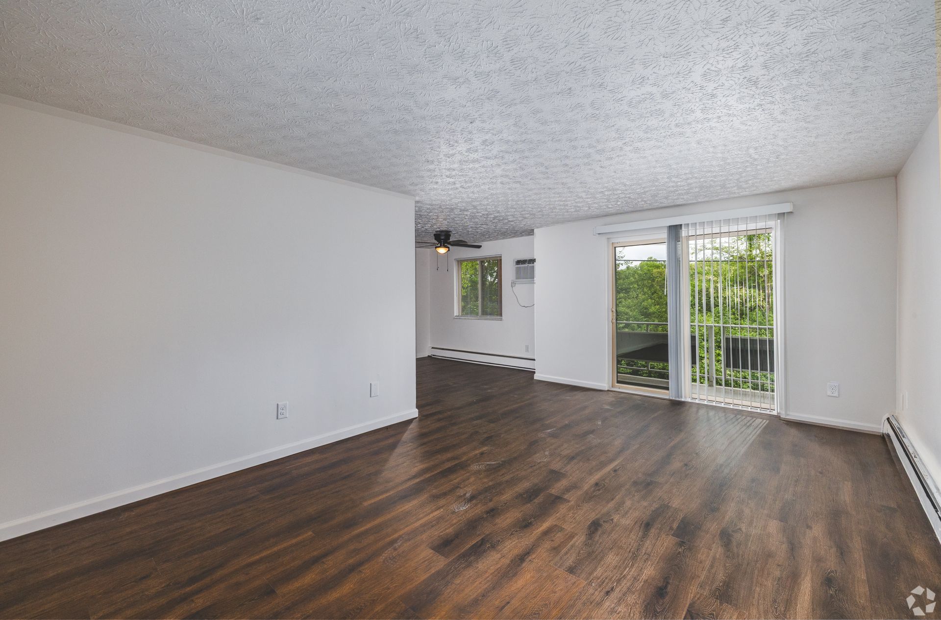 Open living room at Overlook at Sunset with wood-style flooring, patio door, and natural light.