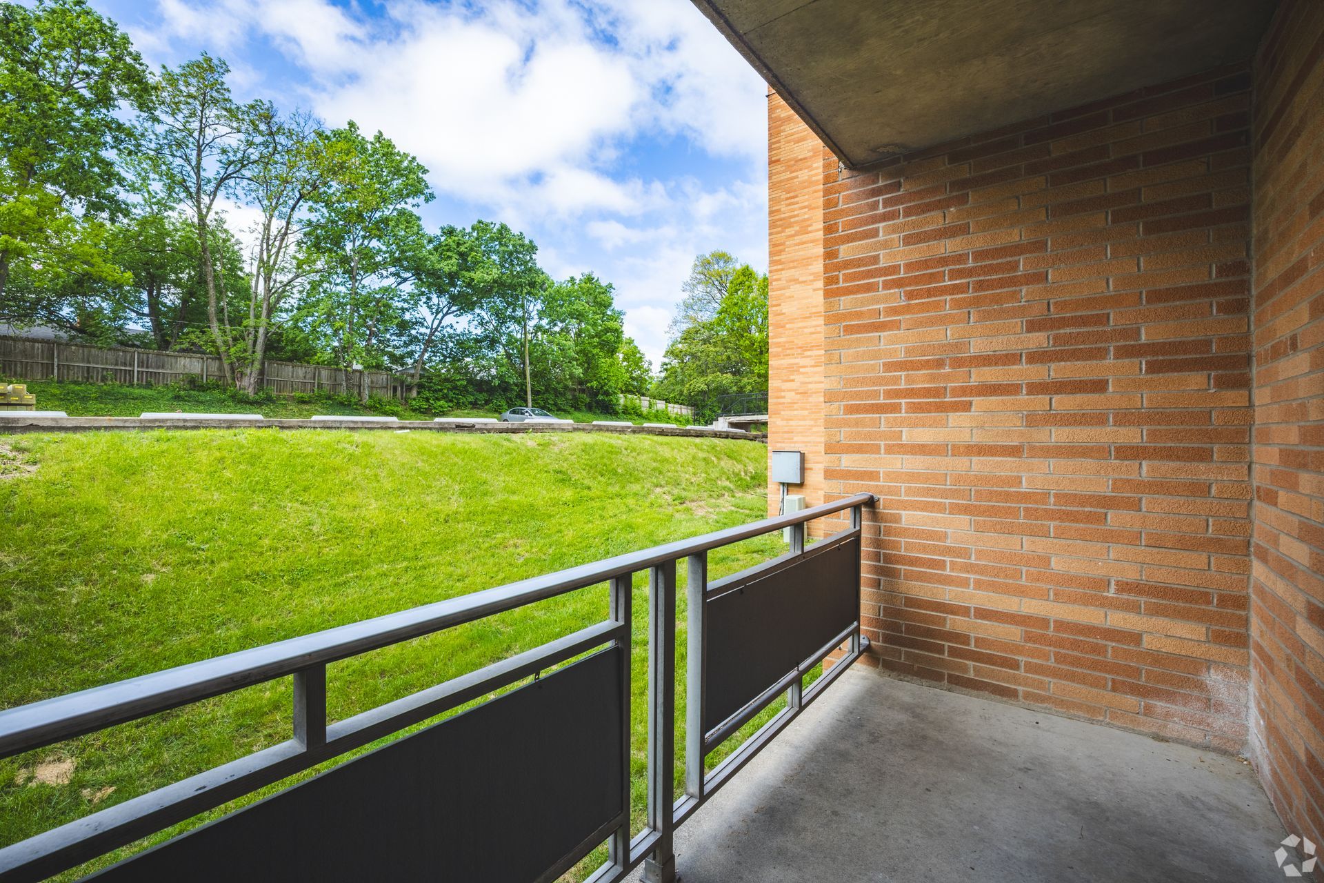 Private balcony at Overlook at Sunset overlooking green lawn, trees, and outdoor space.