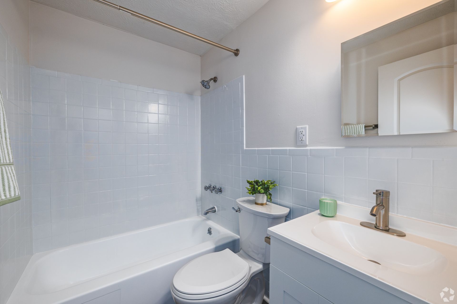 Bathroom at Overlook at Sunset with bathtub, vanity, mirror, and light tile shower surround.