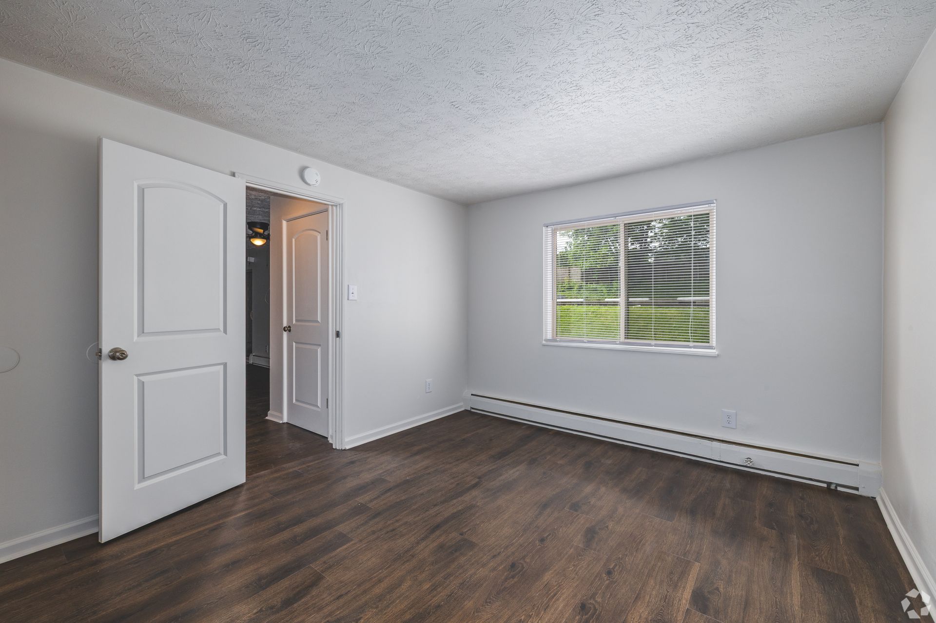 Bedroom at Overlook at Sunset with wood-style flooring, neutral walls, and a window for natural light.