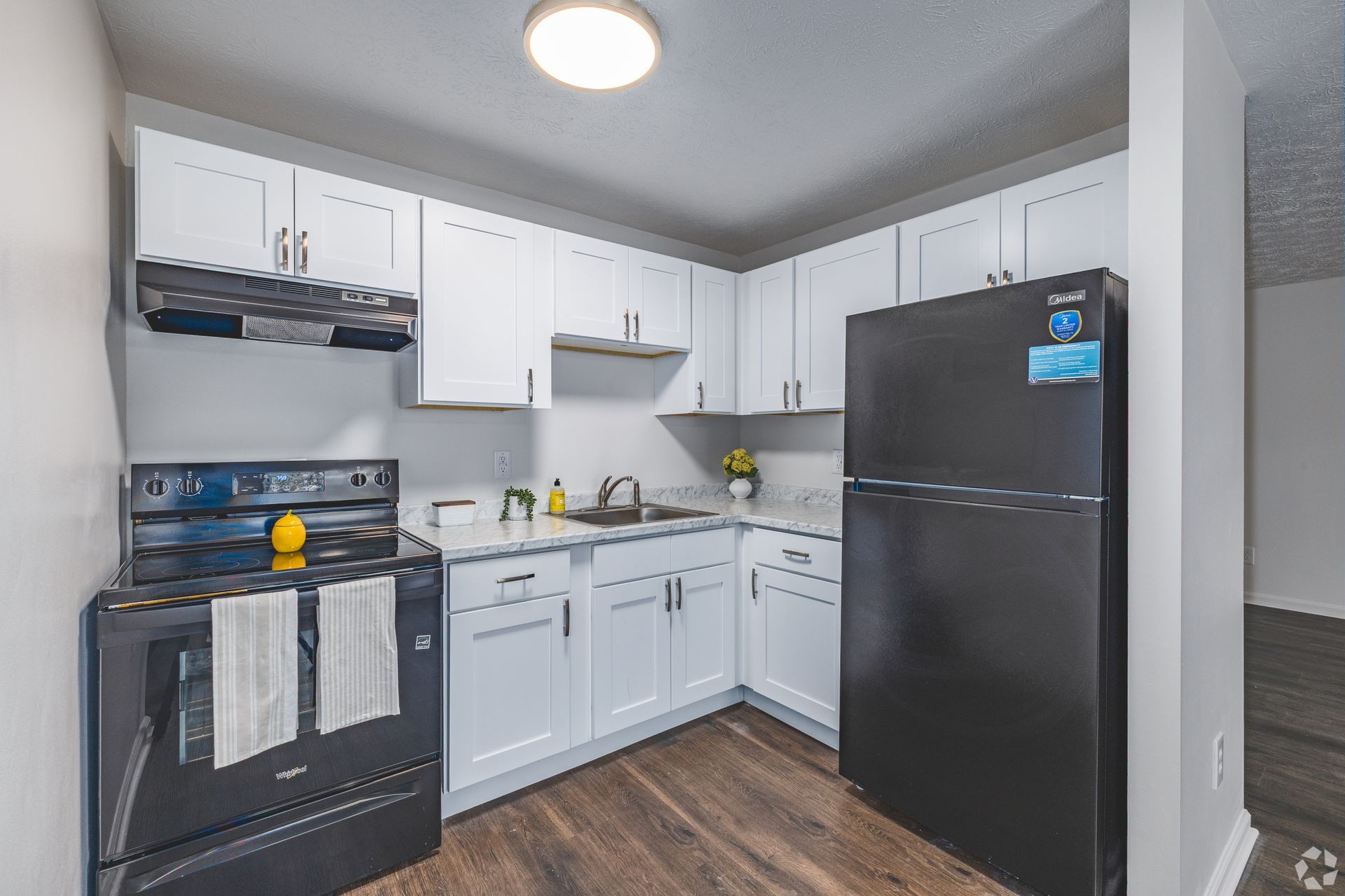 Updated kitchen at Overlook at Sunset with white cabinetry, black appliances, and wood-style flooring.