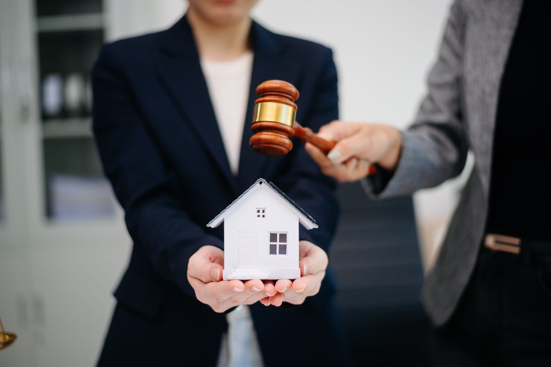 Judge gavel striking next to house model.