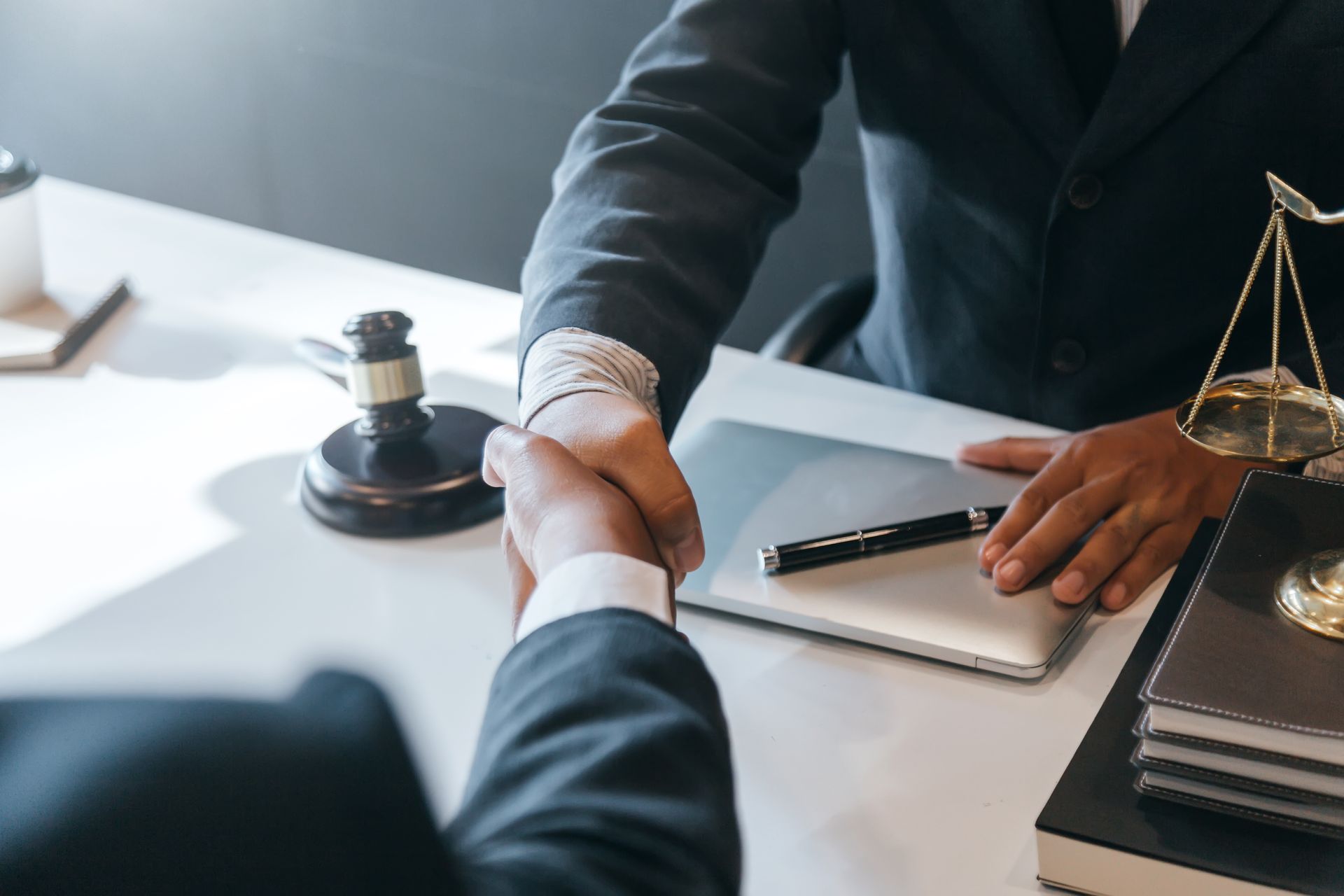 A drug criminal defense attorney is shaking hands with their client at his office.