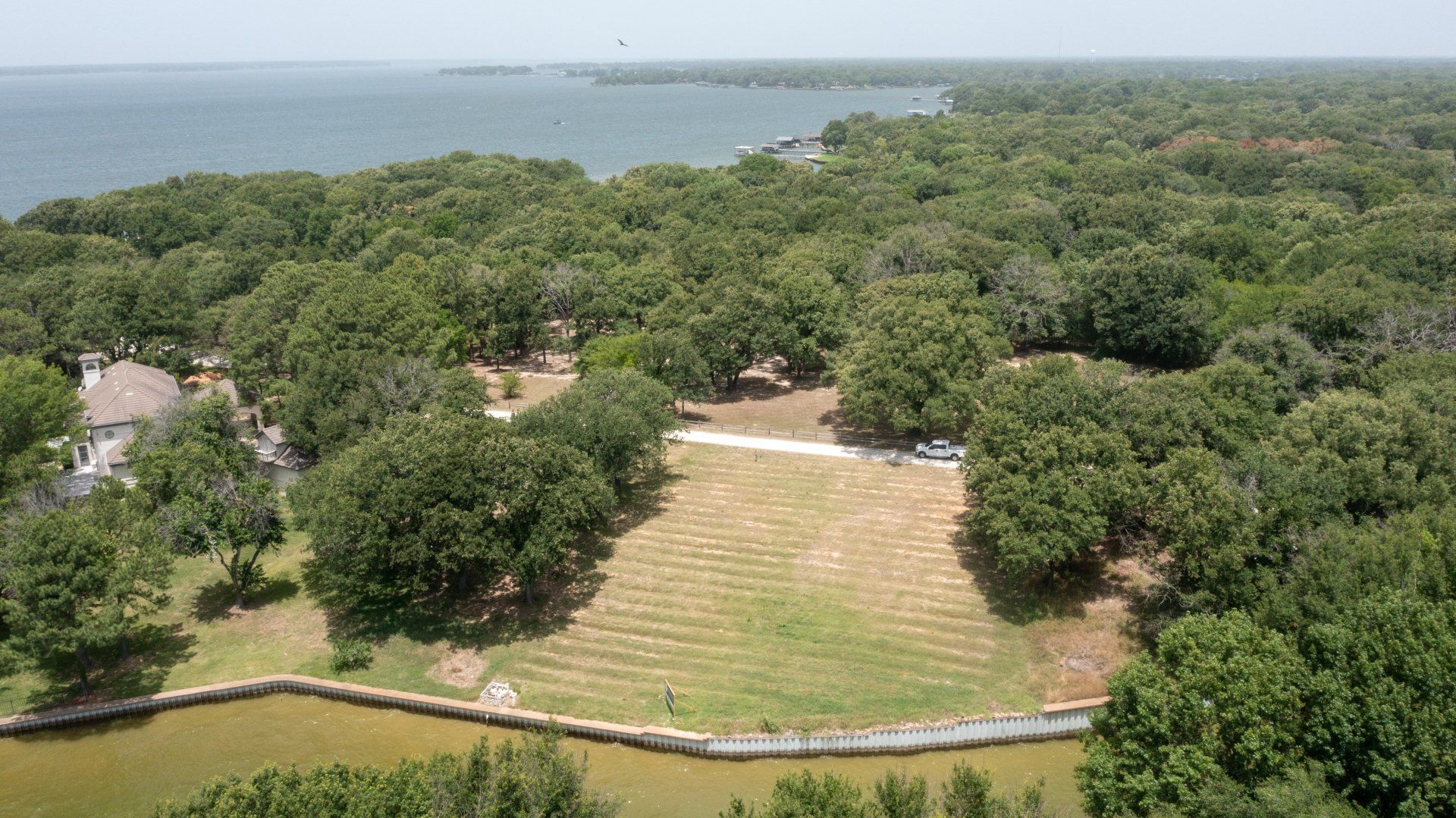 An aerial view of a large field surrounded by trees and a body of water.