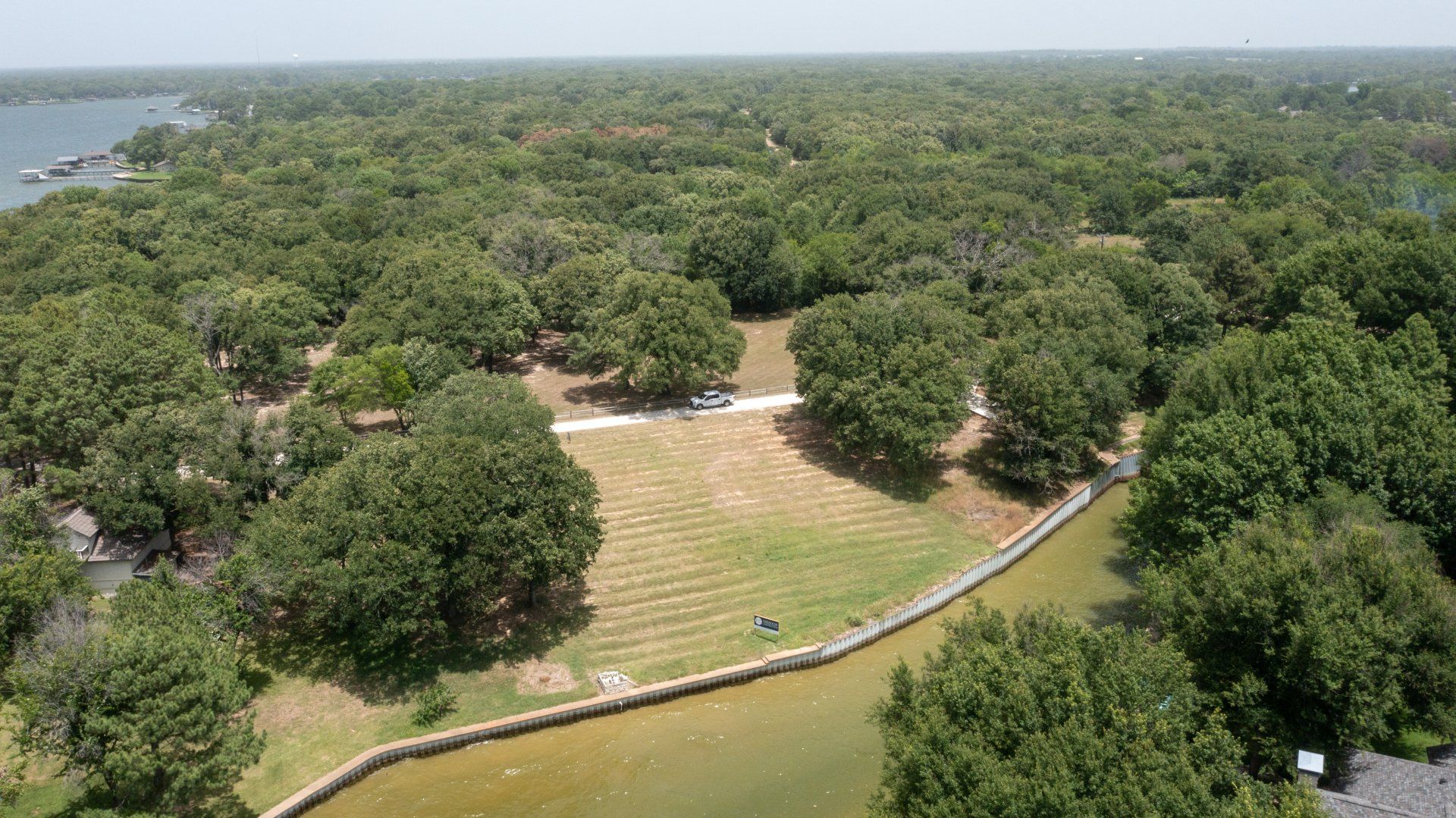 An aerial view of a park with trees and a lake in the background