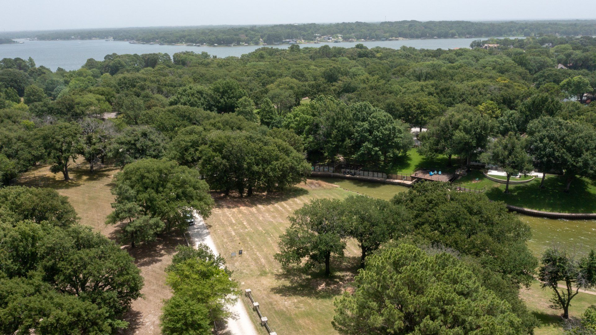 An aerial view of a park with trees and a lake in the background