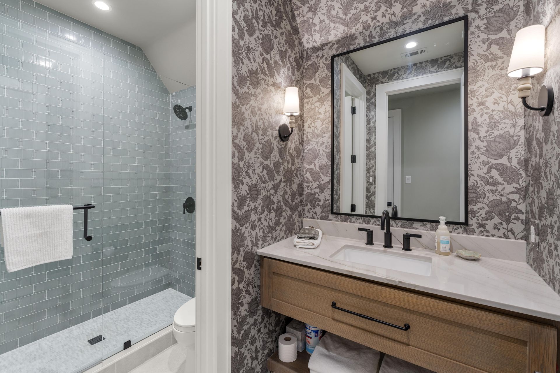 A bathroom with a sink , mirror and shower.