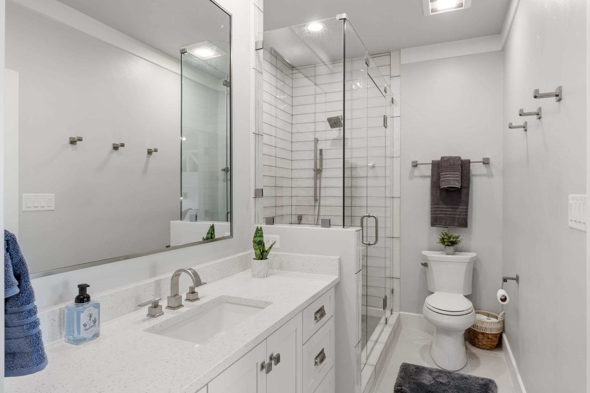 A bathroom with a toilet , sink , mirror and shower.