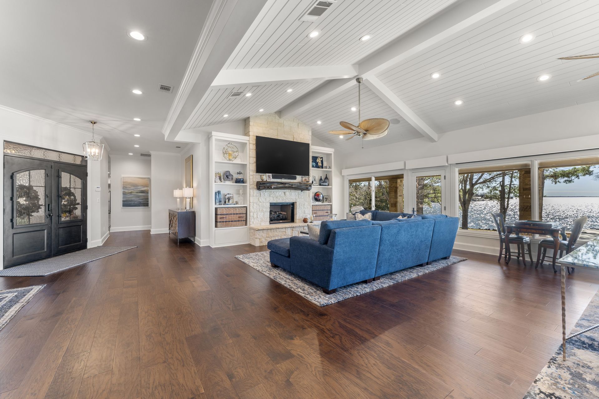 A living room with a blue couch , fireplace , television and hardwood floors.