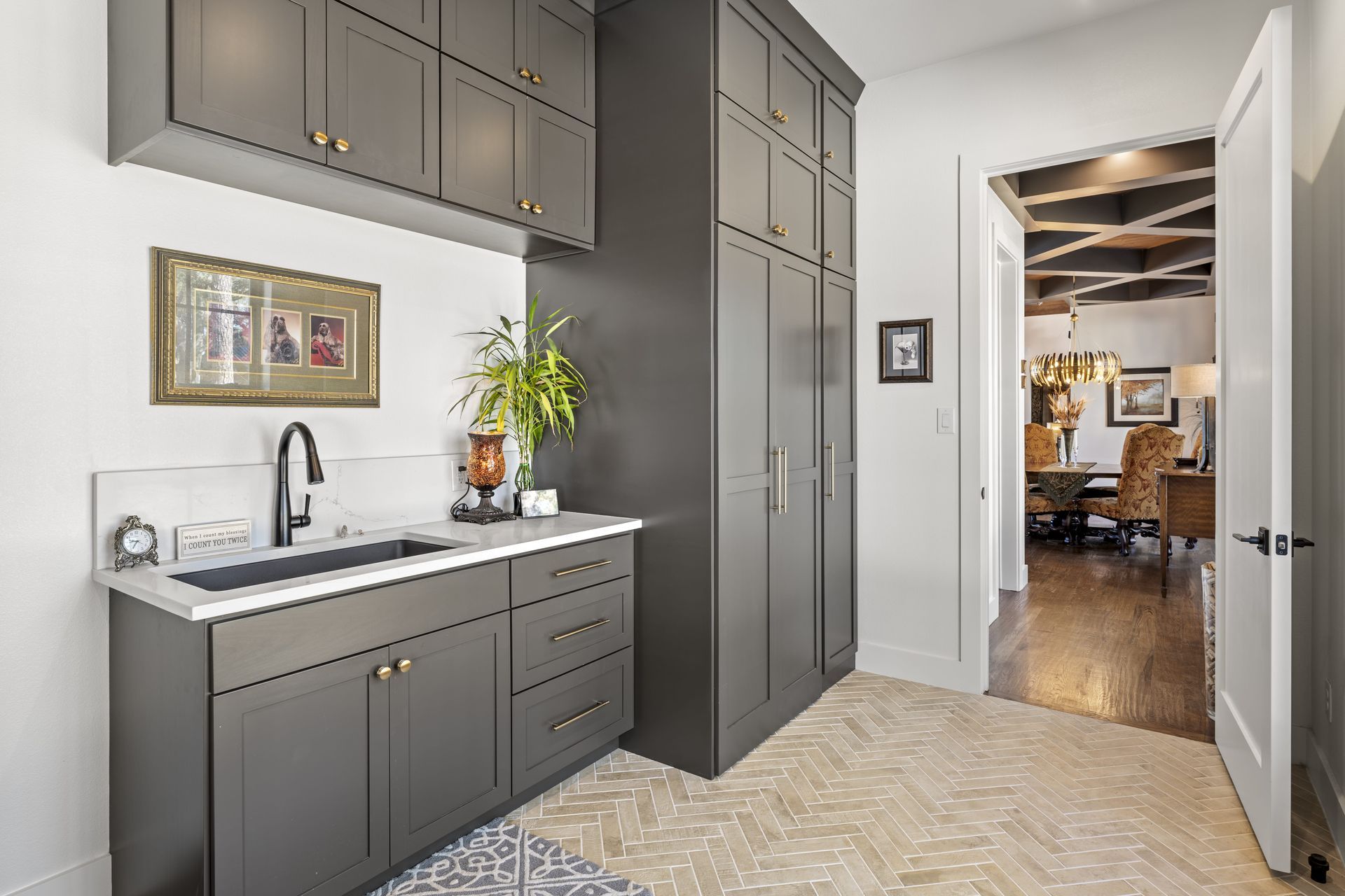 A kitchen with a sink , cabinets , and a door leading to a dining room.