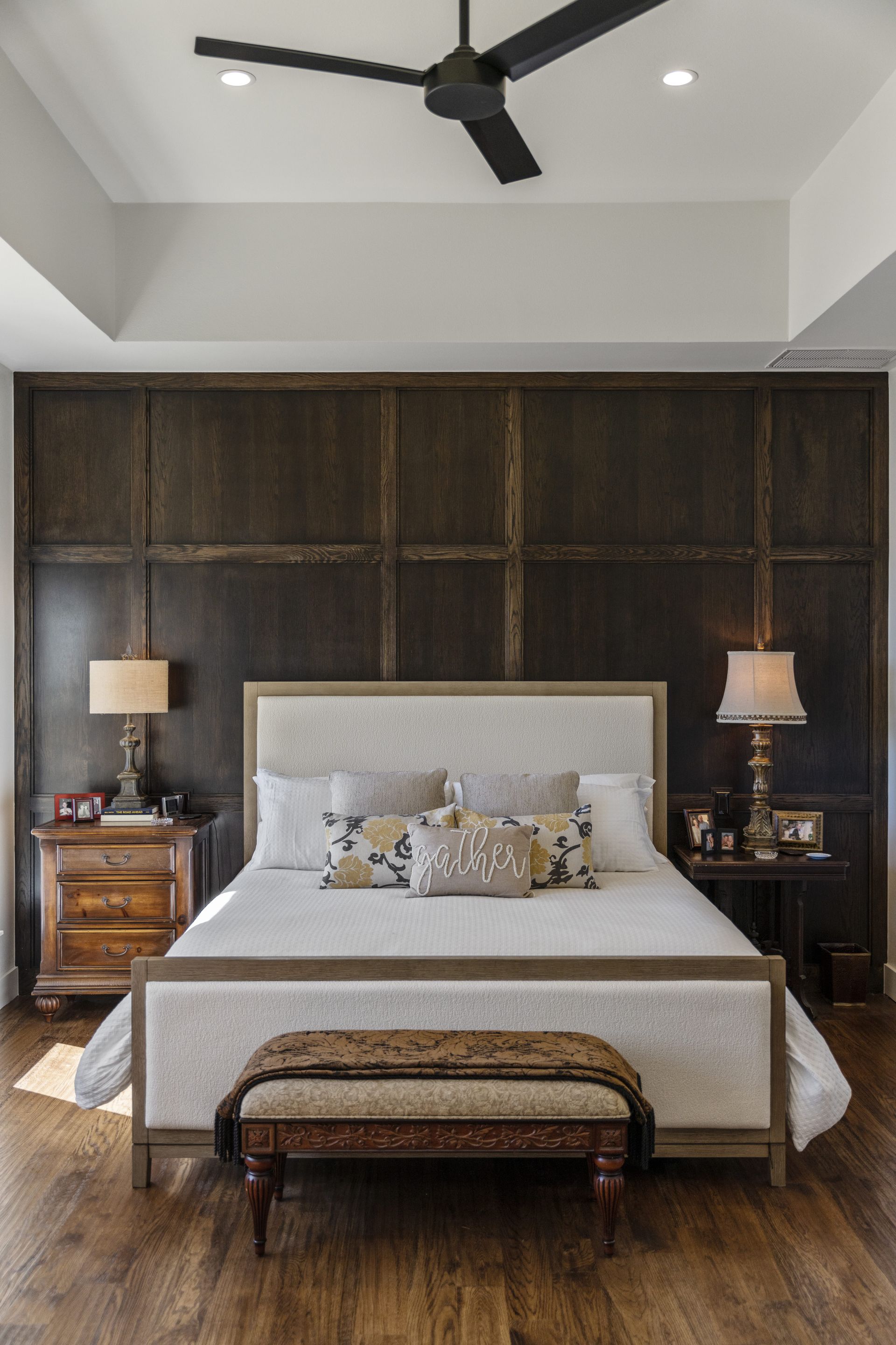 A bedroom with a bed , nightstands , lamps and a ceiling fan.