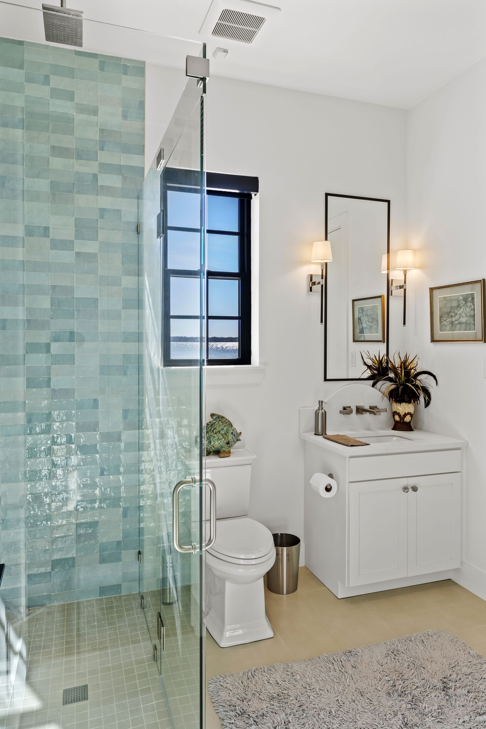 A bathroom with a toilet , sink , mirror and walk in shower.