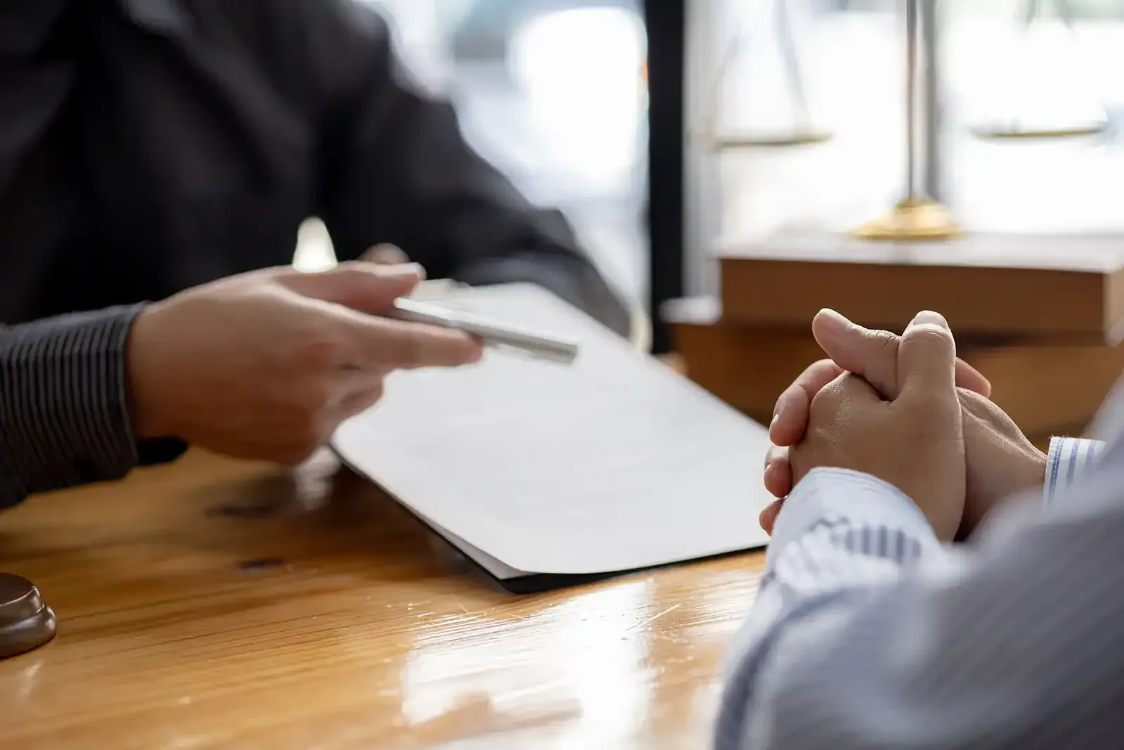 Two people discussing a document across a wooden table in a bright office