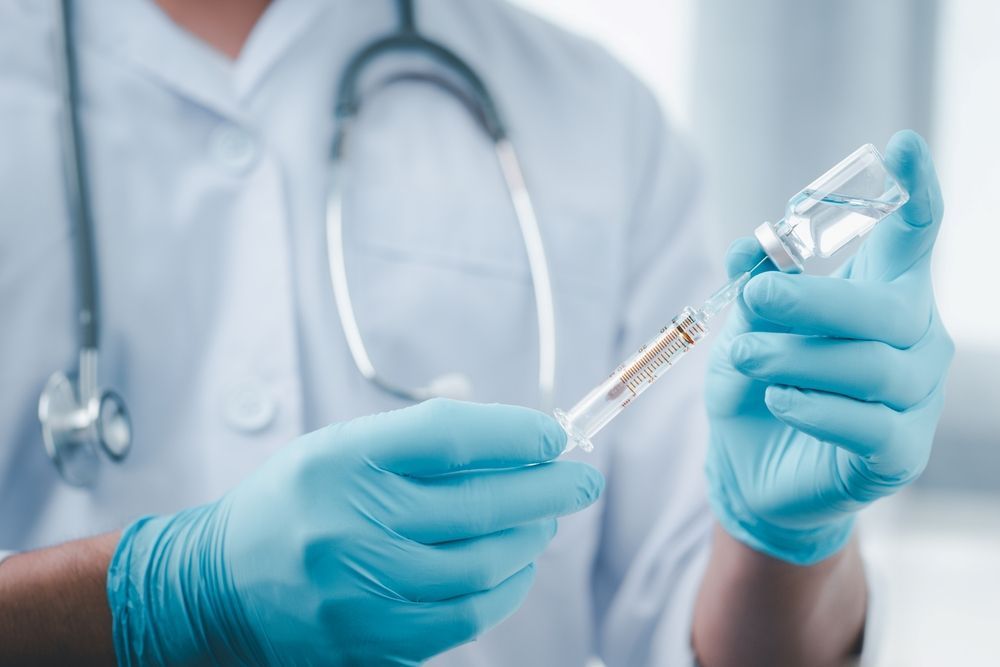 Person in Blue Gloves Filling Syringe From Vial — Mount Archer Medical Centre in Berserker, QLD