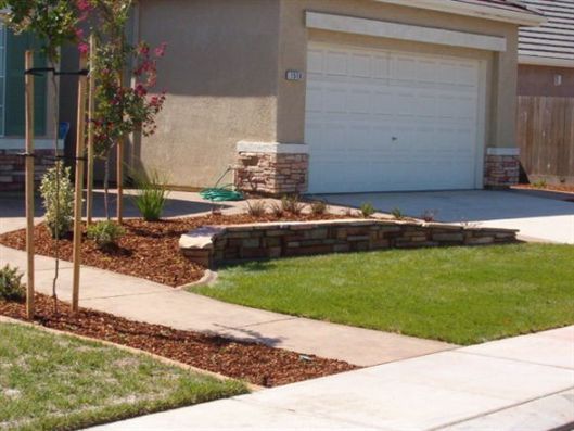 Suburban house entrance with a white garage door, concrete walkway, and landscaped front lawn