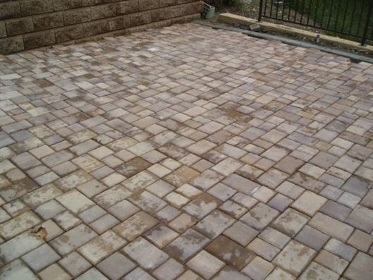 Stone-tiled patio with a brick wall and steps in the background
