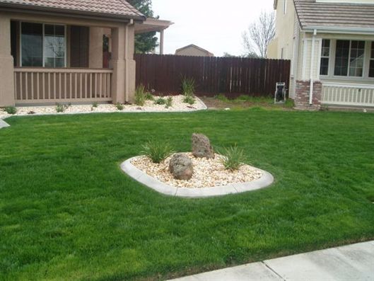 Backyard lawn with a small rock garden in the center between two houses