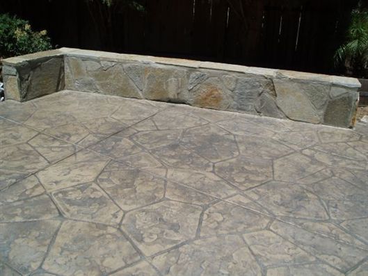 Stone patio with a built-in stone bench against a dark wall.