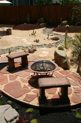 Backyard fire pit on a stone patio beside a dry desert garden with rocks and succulents