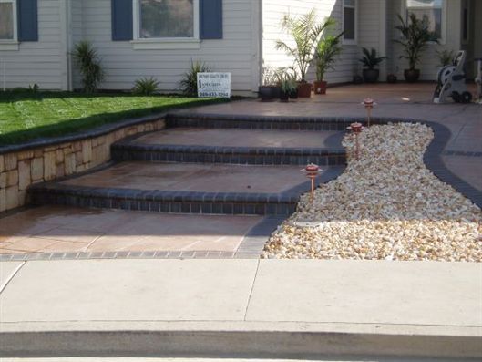 Front steps leading to a house entrance, with brick risers and a gravel path beside them.