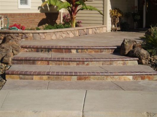 Brick front steps leading up to a house entrance, bordered by rocks and desert plants.