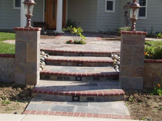 Front steps with brick and stone retaining walls leading to a house entrance